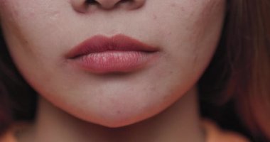 Genç Asyalı bir kadının yüzünün alt kısmını gösteren detaylı bir yakın çekim. Dudaklarını ve deri dokusunu renklendiriyor..
