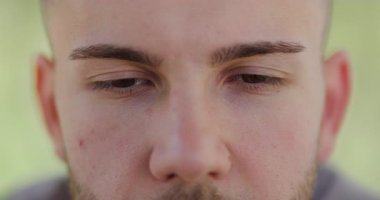 Genç bir adam huzurlu bir şekilde gözleri kapalı, öğleden sonra güneşinde sükuneti kucaklayarak, iç huzuru sağlamak için bilinçlilik ve rahatlama teknikleri uyguluyor..