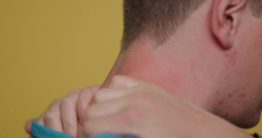 Rahatlatıcı bir omuz masajından hoşlanan bir adam, aydınlık ve rahat bir yerde dinlenir. Odanın ılık tonları rahatlatıcı atmosferi güçlendiriyor..