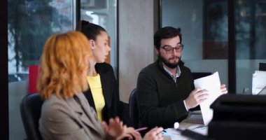 Takım üyeleri öğleden sonra çalışma saatlerinde bir ofiste birlikte çalışırlar. Not alırken belgeleri tartışıp fikir alışverişinde bulunuyorlar. Takım çalışması ve işbirliğine odaklan.