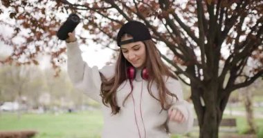 Tasasız Genç Kız Parkta Dans Ediyor, Kulaklıklarındaki Müzikten ve Güzel Bir Bahar Günü Portatif Hoparlöründen Hoşlanıyor