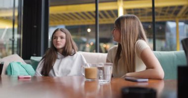 İki genç kız sohbet etmekten ve kafede içmekten zevk alır. Hikayelerini paylaşıyorlar ve birlikte gülüyorlar..