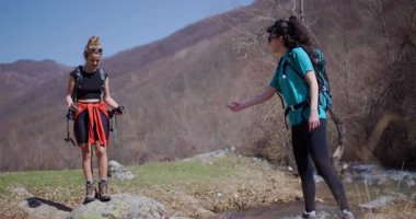 İki bayan arkadaş doğa yürüyüşünün keyfini çıkarıyorlar, dereyi geçip nehir kenarında mola veriyorlar. Gülüşlerini paylaşıyorlar ve güzel manzaranın tadını çıkarıyorlar..