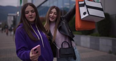 Heyecanlı iki genç kız alışveriş merkezinin önünde selfie çekerek başarılı alışverişlerini kutluyor..