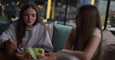 İki genç kız bir kafede sağlıklı bir yemek ve sohbet etmekten zevk alır. Mutlular ve gülümsüyorlar..