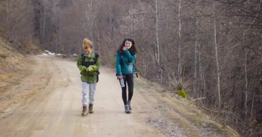 İki bayan arkadaş dağlardaki toprak yolda yürüyüş yapmaktan zevk alıyor. Mutlular ve eğleniyorlar..