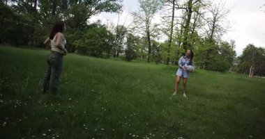 İki bayan arkadaş, yemyeşil ağaçlarla çevrili bir parkta voleybol oynuyorlar. Kahkaha ve aktivitelerle dolu eğlenceli bir gün geçiriyorlar..