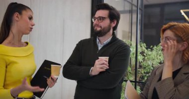 Bir adam ve iki kadın ofis ortamında buluşuyorlar. Bitkiler ve büyük pencerelerle çevriliyken düşüncelerini paylaşıyorlar ve kahve içiyorlar. Tartışma odaklanmış ve meşgul görünüyor..