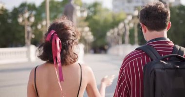 Güneşli bir günde, bir köprüde yürüyen ve konuşan iki kişinin arka plan görüntüsü, şehir keşfi ve boş zamanlarını gösteriyor..