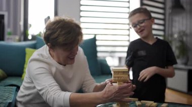 Grandmother and grandson playing a game of blocks. They are having fun and laughing together.