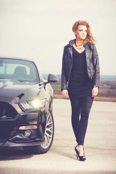 Mujer atractiva joven posando con un coche deportivo al aire libre — Foto de Stock