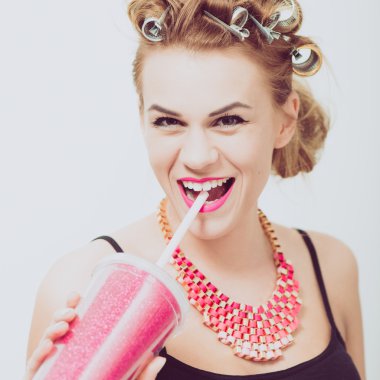 İçme, bir saman kullanarak mutlu, genç kadın. Curlers saç.