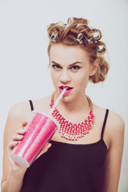 İçme, bir saman kullanarak mutlu, genç kadın. Curlers saç.