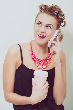 Cep telefonu evde kullanan genç kadın. Onun el ve saçında curlers içecekler.