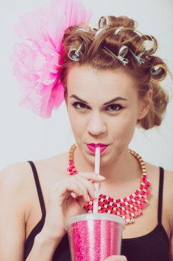 İçme, bir saman kullanarak mutlu, genç kadın. Curlers saç.