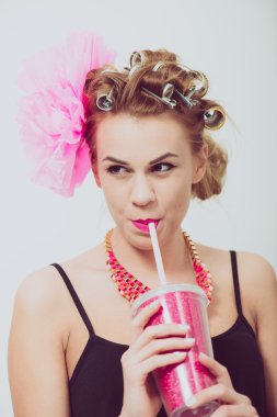 İçme, bir saman kullanarak mutlu, genç kadın. Curlers saç.