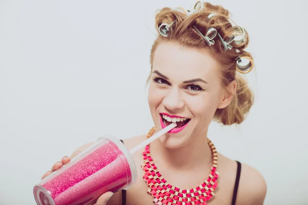 Feliz, jovem bebendo, usando uma palhinha. Curlers em seu cabelo . — Fotografia de Stock