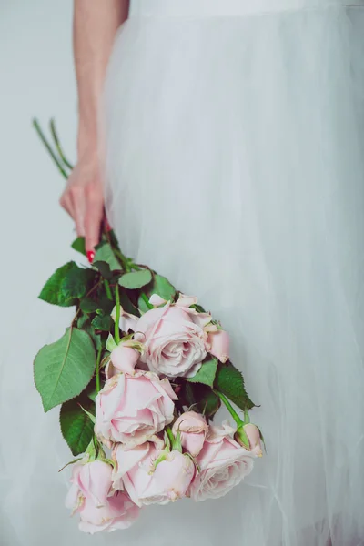 Portret van een bruiloft bruid poseren in een witte jurk met bloemen in haar handen. Mooie bruiloft boeket in handen van de bruid. — Stockfoto