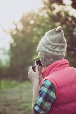 Bir fincan sıcak bir içecek açık havada tutan aktif kadın