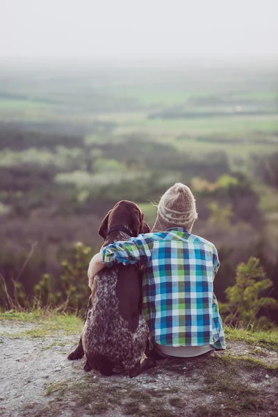 Frau und Hund posieren im Freien. Mädchen liebt und umarmt ihren Hund und beobachtet die Landschaft. — Stockfoto