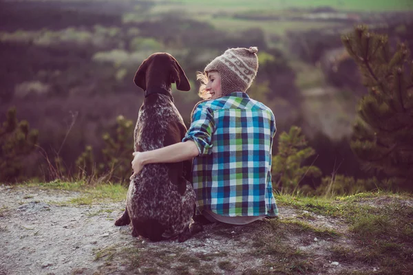 Kvinna och hennes hund poserar utomhus. Flicka kärleksfull och kramas hårt hennes hund och titta på landskapet. — Stockfoto