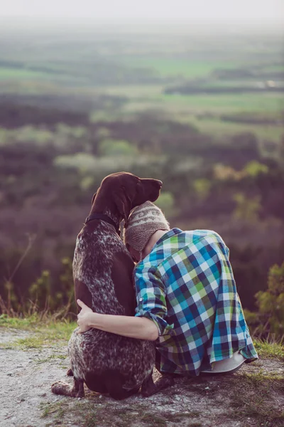 Kvinna och hennes hund poserar utomhus. Flicka kärleksfull och kramas hårt hennes hund och titta på landskapet. — Stockfoto