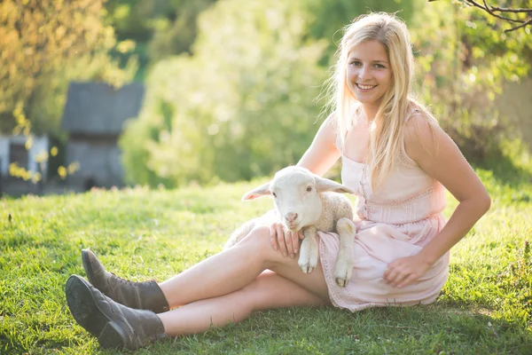 Immagine ravvicinata di agnello carino, giovane prendersi cura di donna contadina. Donna felice sorridente e in possesso di un agnello carino . — Foto Stock