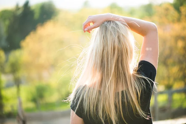 Blondine posiert bei Sonnenuntergang im Freien. Landschaft beobachten. — Stockfoto