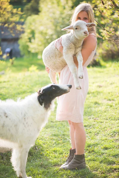 Lycklig blond kvinna leker med sin ryska varghund hund i trädgården — Stockfoto