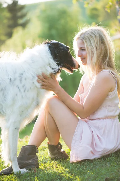 Boldog szőke nő játszik vele orosz farkaskutya kutya kertben — Stock Fotó