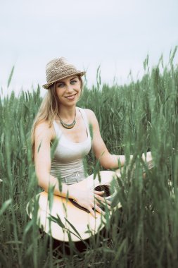 genç kadın alanında oturup ve gitar çalmak