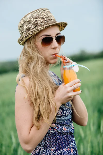 Женщина пьет апельсиновый сок улыбаясь и позируя на открытом воздухе . — стоковое фото