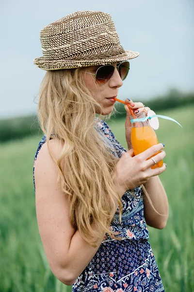 Frau trinkt Orangensaft lächelnd und posiert im Freien. — Stockfoto