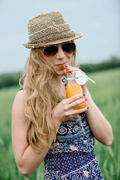 Frau trinkt Orangensaft lächelnd und posiert im Freien. — Stockfoto