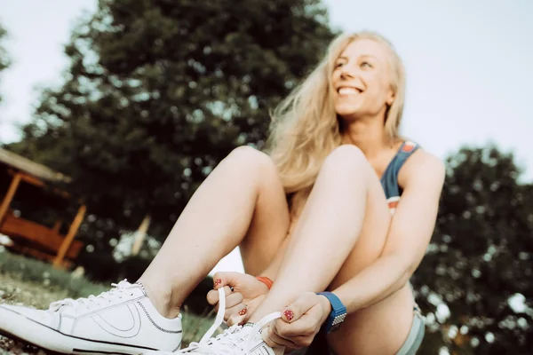 Молода атлетична жінка зв'язує шнурки на відкритому повітрі — стокове фото