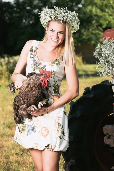 Agricultor loiro mulher segurando um galo — Fotografia de Stock