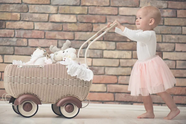 Baby girl with toy baby carriage — Stock Photo, Image