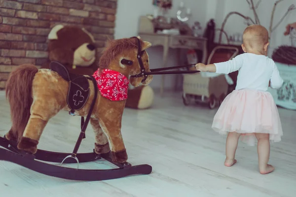 Младенец играет с скачущей лошадью — стоковое фото