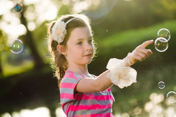 Leuk meisje achter zeepbellen — Stockfoto