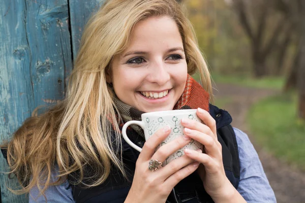 Lächelnde modische Blondine trinkt Heißgetränk — Stockfoto