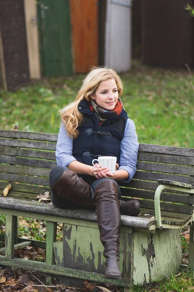 Smiling fashionable blonde drinking hot beverage — Stock Photo, Image