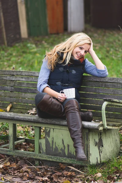 Smiling fashionable blonde drinking hot beverage — Stock Photo, Image