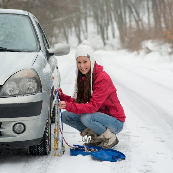 Mulher colocando correntes de pneus de inverno na roda do carro quebra de neve — Fotografia de Stock