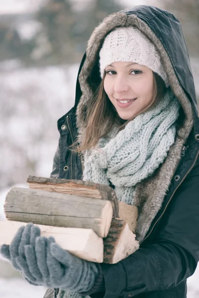 Stijlvolle jonge vrouw poseren met gehakte firedwood op winter voorbereid. — Stockfoto