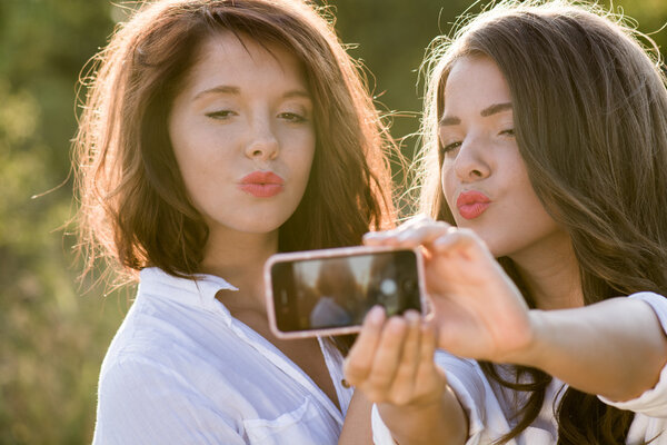 Friends making selfie. Two beautiful young women making selfie and grimacing