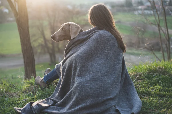 Mulher com seu belo cão deitado ao ar livre, assistindo ao pôr do sol — Fotografia de Stock