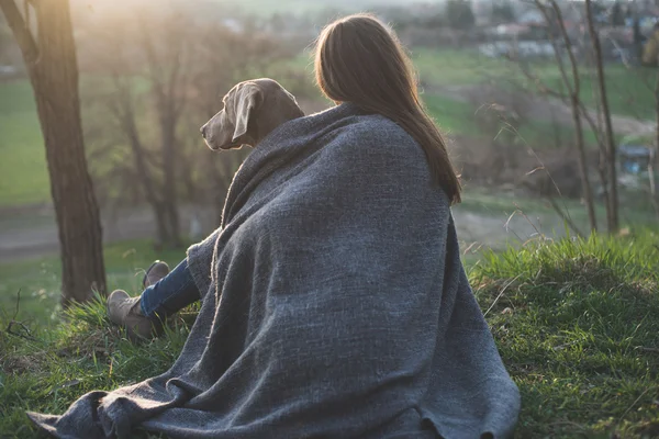 Vrouw met haar mooie hond liggen buiten, kijken naar zonsondergang — Stockfoto