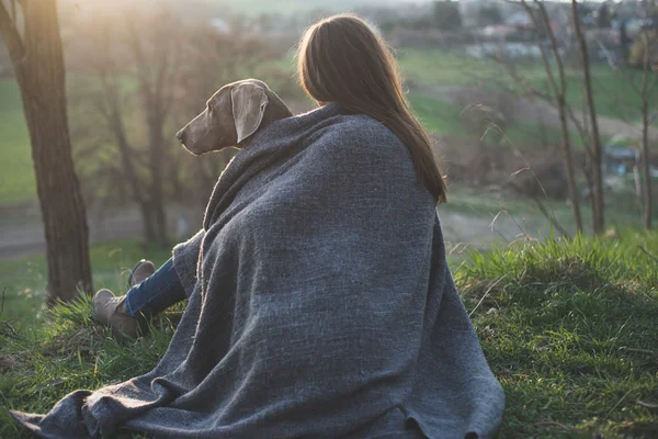 Kvinna med hennes vackra hund ligga utomhus, titta på solnedgången — Stockfoto