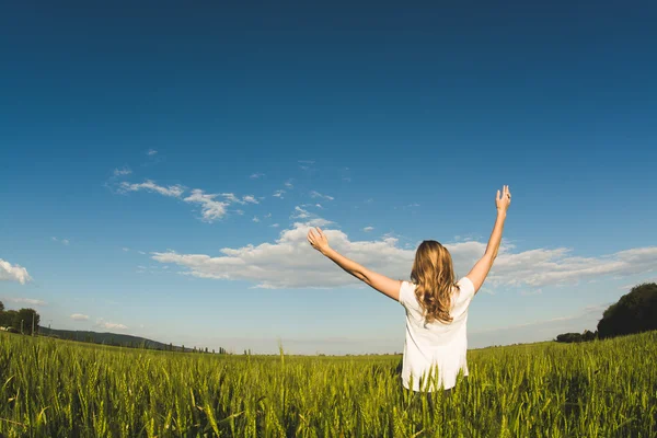 Junge Frau genießt Natur und Sonnenlicht im Weizenfeld — Stockfoto