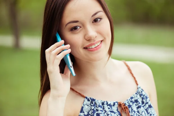 미소짓고 있는 젊고 아름다운 여자가 휴대폰으로 이야기하는 모습 — 스톡 사진